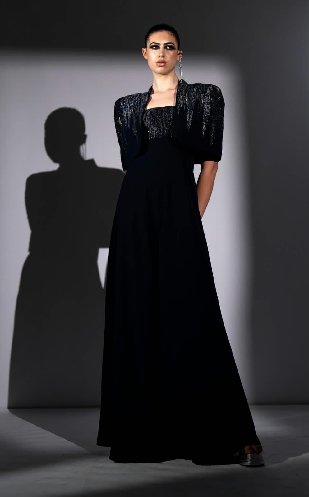 The Eclipse gown from the front, a midnight beaded bolero over a slim floor-length column, cast against a hard studio shadow.